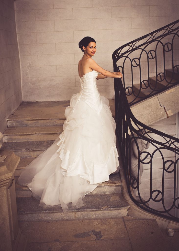 Bride on stairway with dress flowing behind